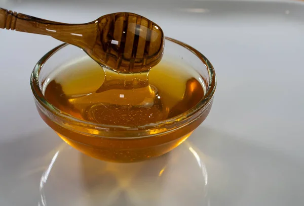 Glass bowl plate with honey wood spoon, dipper, white background, copy space — Stock Photo, Image