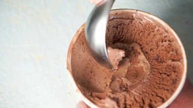 Çikolata yapan kadın, metal kaşıkla dondurma topunu ısırıyor. 4K yakın çekim.
