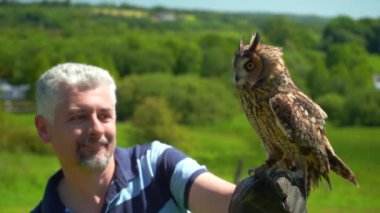 Eldivenli bir adam uzun kulaklı bir baykuş gibi yavaşça uçuyor.