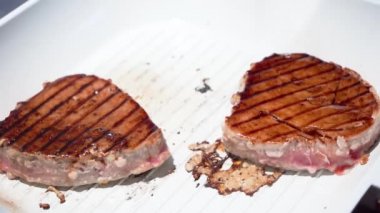 El, soya soslu ton balığı bifteğini silikon fırçasıyla kaplıyor ve baharat serpiyor.