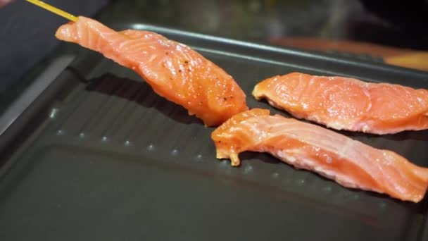 Vrouwelijke hand zet op pan rauwe zalm spiesen met soja limoen bbq saus natuurlijk voedsel — Stockvideo