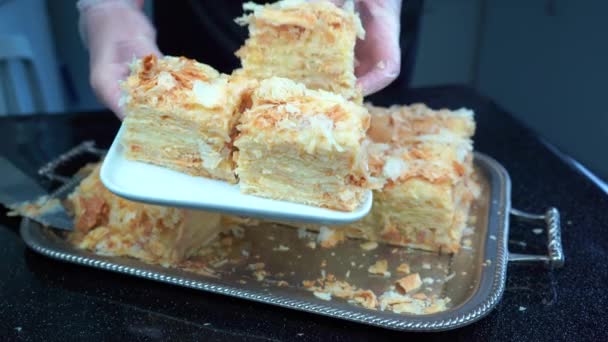 Χέρια σε γάντια βινυλίου βάλει κρέμα layered κέικ σφολιάτας Ναπολέων σε λευκό πιάτο — Αρχείο Βίντεο
