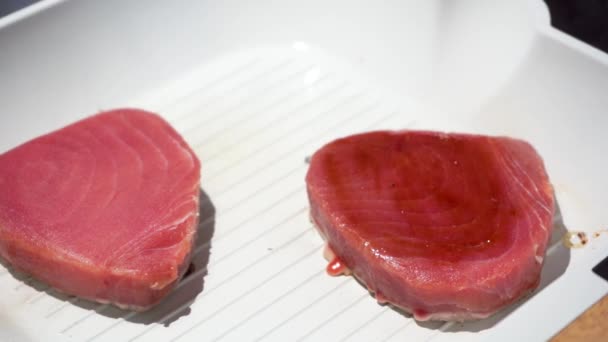 Mão feminina cobre bife de atum com molho de soja com escova de cozinha de silicone na panela — Vídeo de Stock