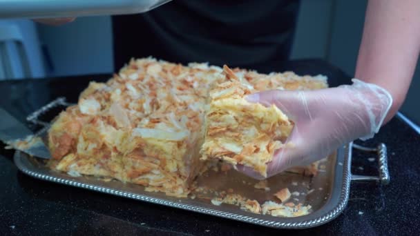 Las manos en guantes de vinilo ponen crema en capas pastel de hojaldre Napoleón en el plato blanco — Vídeo de stock