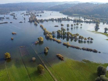 sel basmış vadi yeşil tarlalar ve ağaçlar