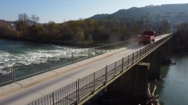 Kamyon engebeli bir nehrin üzerindeki köprüden geçiyor.