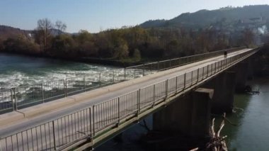 Bir bisikletçi engebeli nehrin üzerinden köprüyü geçiyor.