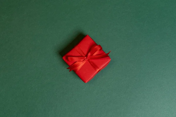 Ένα κόκκινο δώρο Χριστουγέννων τυλιγμένο σε πράσινο φόντο — Φωτογραφία Αρχείου