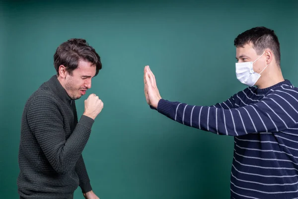 Man in mask fencing off coughing guy Stock Picture