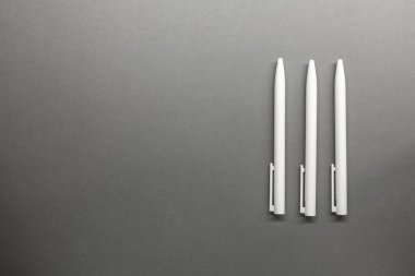 Gri masa arkaplanında üç beyaz top kalemi