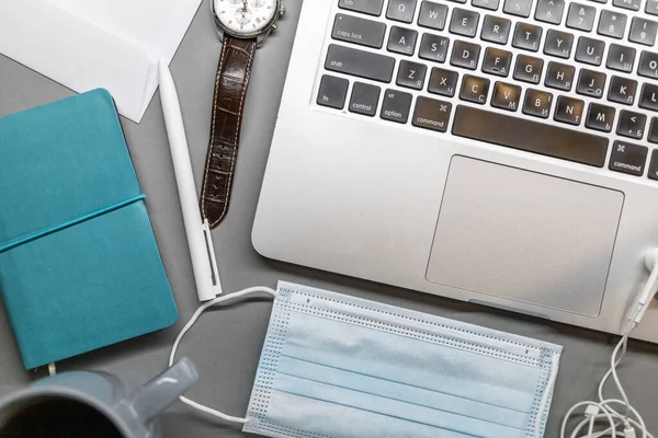 Notebook laptop gezichtsmasker horloge en pen op grijze tafel — Stockfoto