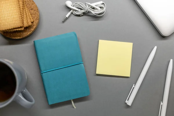 Blauw notebook cup koekje en pennen op grijze tafel — Stockfoto