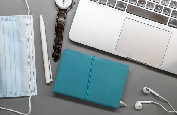 Notebook laptop gezichtsmasker horloge en pen op grijze tafel — Stockfoto