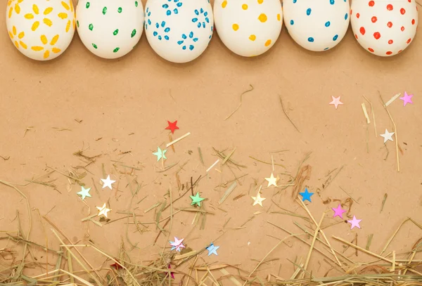 Spotted easter eggs on kraft background with hay — Stock Photo, Image