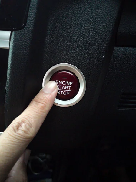 Fingers press the engine start button