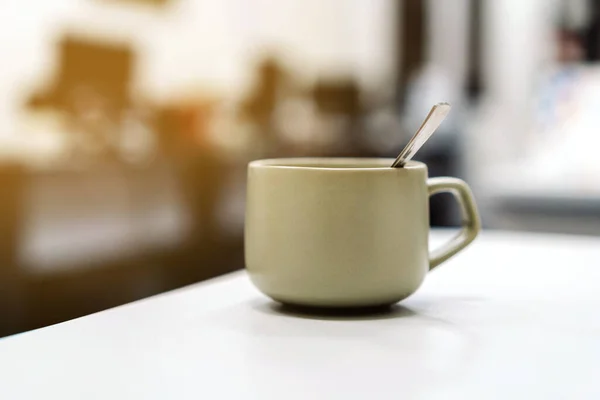 Mug with a hot drink on the background of a blurry office