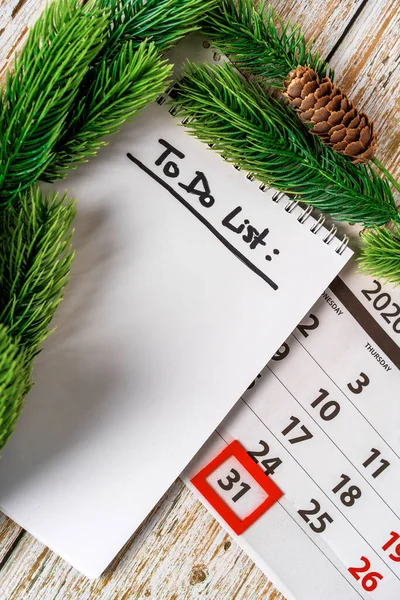 December calendar and notepad with to do list on a wooden background top view. The concept of planning Christmas