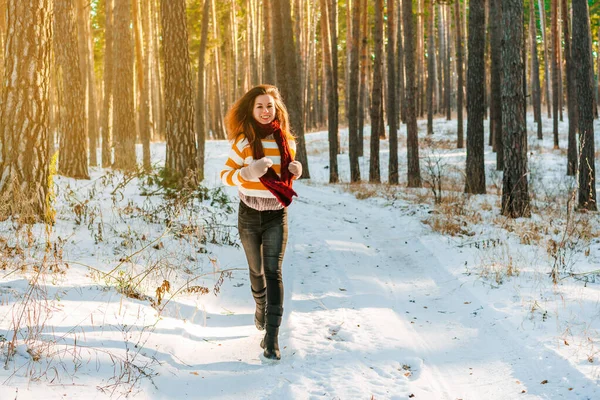 冬の松林の雪景色を背景にしたセーター姿の若い女性の肖像 — ストック写真