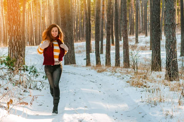 Portrait of a young woman in a sweater on the background of a snowy landscape in a winter pine forest