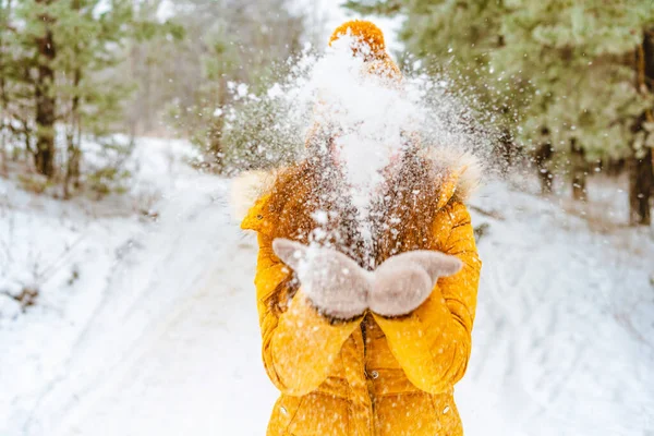 黄色のジャケットと帽子の美しい若い女性は雪の冬の森の中で雪を投げる — ストック写真