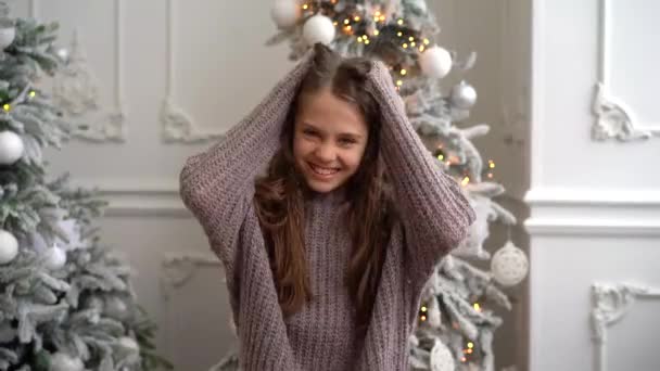 暖かいセーターを着た巻き毛の少女が顔を作って笑って楽しんでる — ストック動画