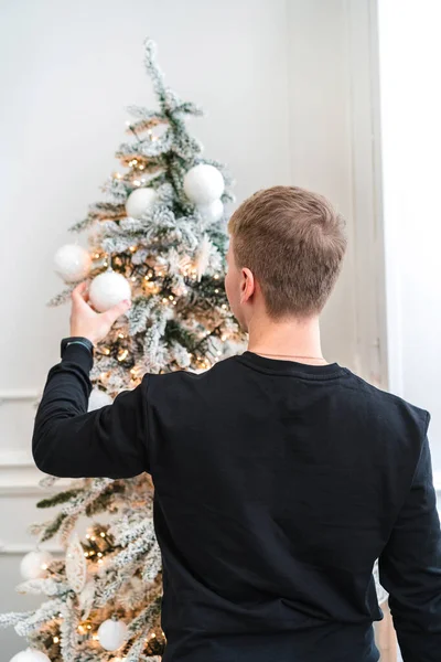 Ένας Όμορφος Νεαρός Ξανθά Μαλλιά Κρεμάει Παιχνίδια Ένα Χριστουγεννιάτικο Δέντρο — Φωτογραφία Αρχείου