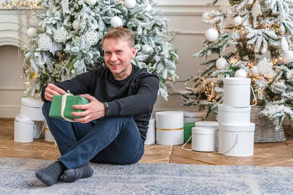 Homem Feliz Com Presentes Ano Novo Sentado Tapete Fundo Natal — Fotografia de Stock