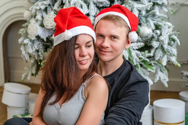 魅力的な幸せなカップル男と女上のクリスマスの日に立って装飾された木の前で互いに目に美しい笑みを浮かべて — ストック写真