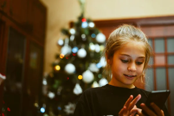 おかしいです女の子遊びます彼女のスマートフォン上のクリスマスイブ — ストック写真