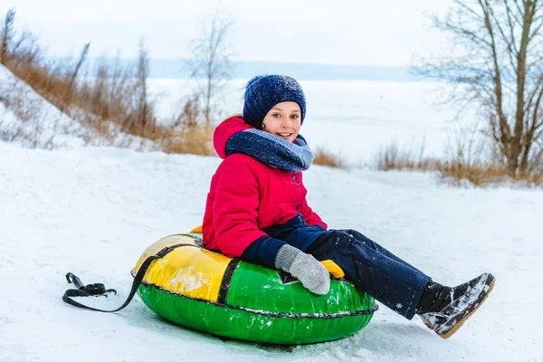 快乐的小女孩坐在管子上滑落在雪地里 带着冬日的欢乐 — 图库照片
