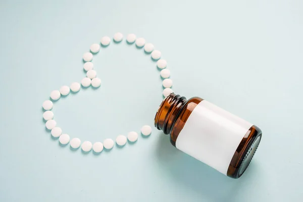 Tablety Nebo Pilulky Skleněné Sklenice Modrém Pozadí Spočívají Formě Srdce — Stock fotografie