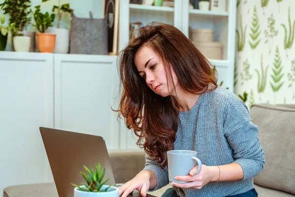 ソファに座っている若い女性のフリーランスの笑顔は 自宅からリモートで働くことを楽しんでいます 幸せな女性学生は屋内オンラインコースで勉強します — ストック写真