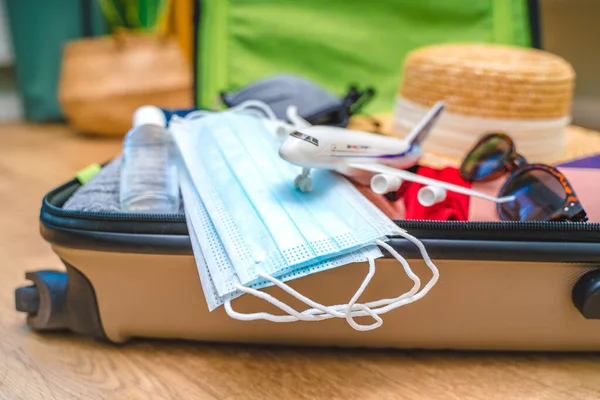 Travel passports, a hat, and medical masks are in an open travel suitcase. Tourism after the opening of borders, the end of quarantine