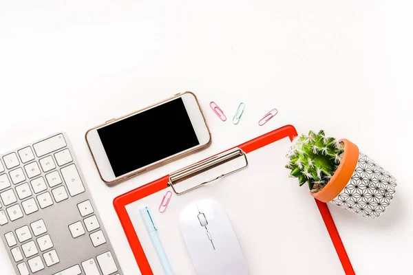 Office background on a white desk with notepad, keyboard and mobile phone. Top view, copy space