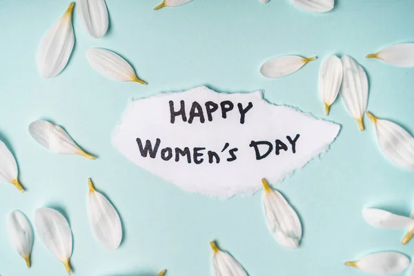 Kawałek Papieru Napisem Happy Women Day Otoczony Białymi Płatkami Niebieskim — Zdjęcie stockowe