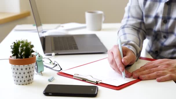 Ein Mann Schreibt Ein Notizbuch Arbeitsfragen Ein Büro Mit Grünen — Stockvideo