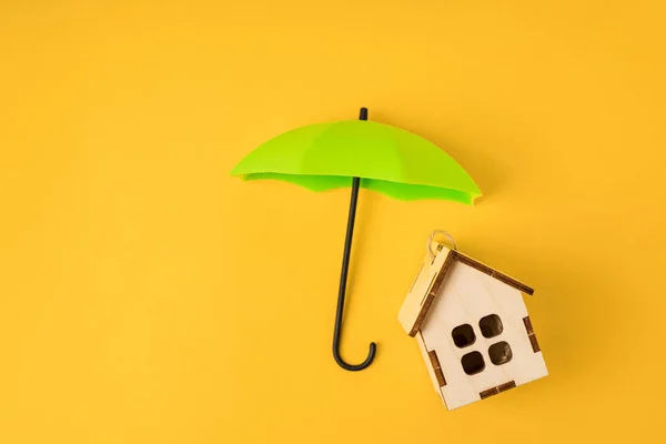 Sarı Arka Plandaki Ahşap Bir Evin Üzerinde Oyuncak Bir Şemsiye — Stok fotoğraf
