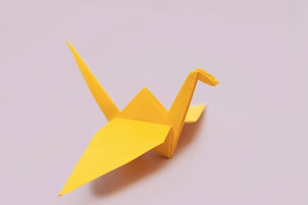 Yellow origami bird on purple background with space for