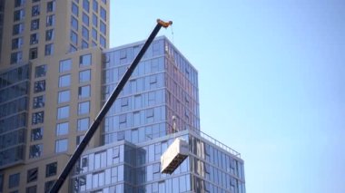 İnşaat vinci bir cam iş binasının arka planına yük kaldırır. Los Angeles, ABD - 14 Nisan 2021