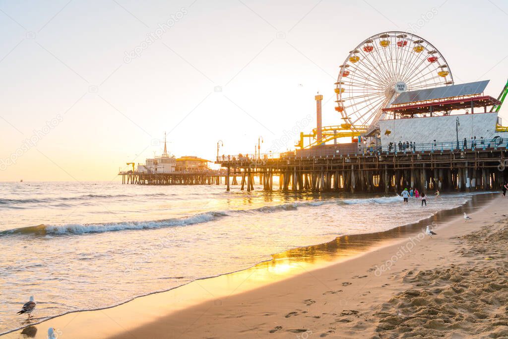 Santa Monica Pier on the background of an orange sunset, calm ocean waves, Los Angeles, California