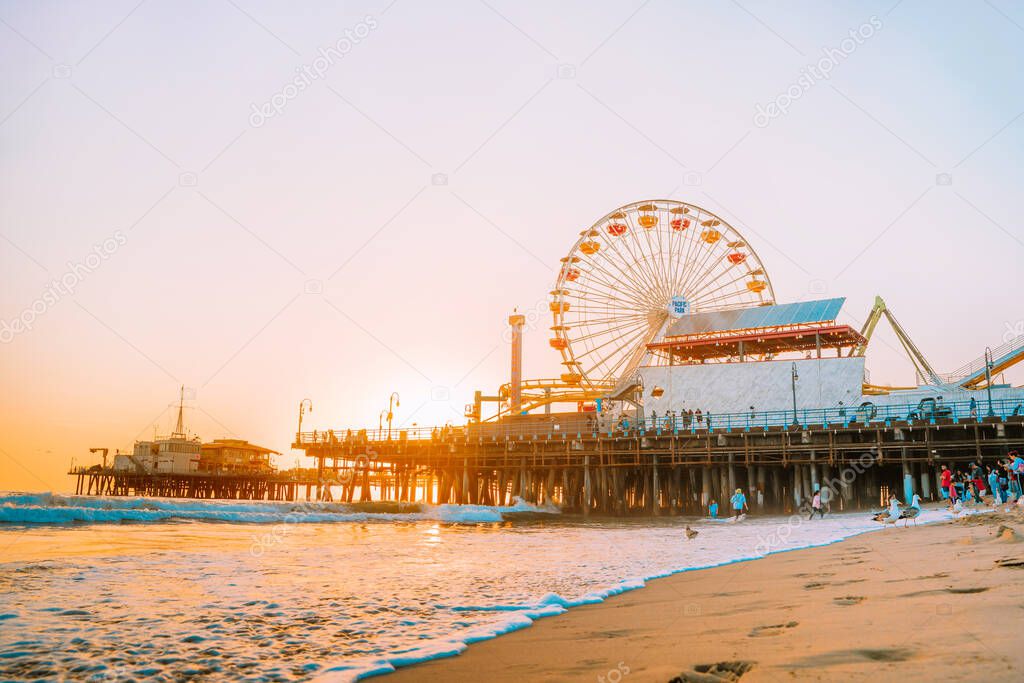 Santa Monica Pier on the background of an orange sunset, calm ocean waves, Los Angeles, California