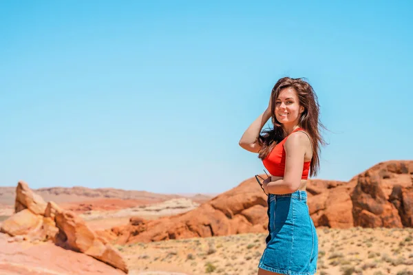 Happy brunette woman in the Valley of Fire in Nevada overlooking a desert landscape