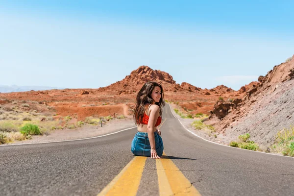 Beautiful young girl in a denim skirt on a scenic road in Valley of fire, Nevada