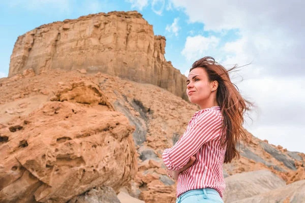 A young woman stands near a huge boulder with a beautiful view of Alstrom Point, Utah, USA