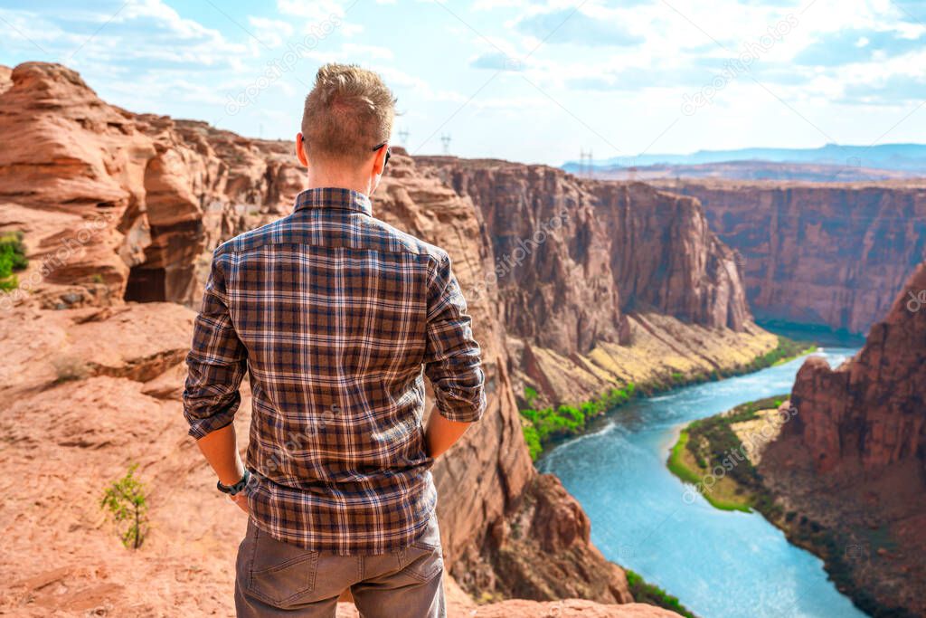 Gorgeous landscape and young man on red rocks overlooking the Colorado River, Arizona