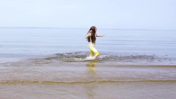 4K视频 穿着黄色裤子的小女孩在河边奔跑 夏天的主题 — 图库视频影像
