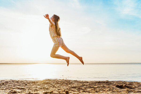 Little girl jumping on the beach in the water, the concept of a fun summer vacation