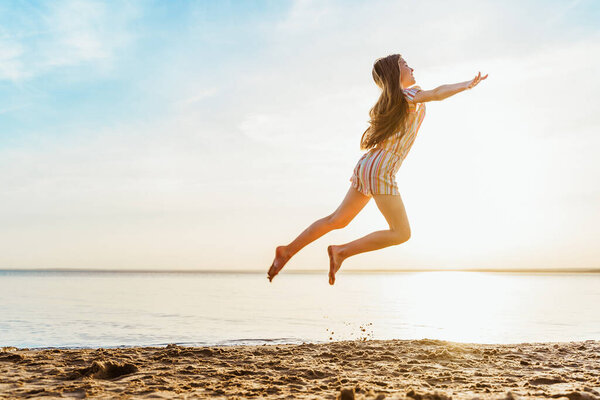 Little girl jumping on the beach in the water, the concept of a fun summer vacation