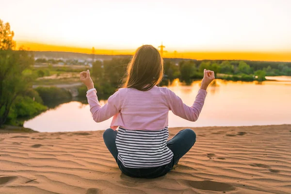 Liten Flicka Barn Som Sitter Yoga Poserar Solnedgången Framför Sjön — Stockfoto