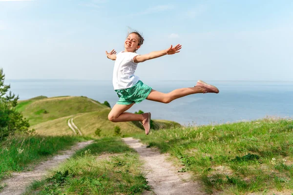 Mała Dziewczynka Radośnie Skacze Powietrze Ścieżką Środku Zielonych Łąk — Zdjęcie stockowe